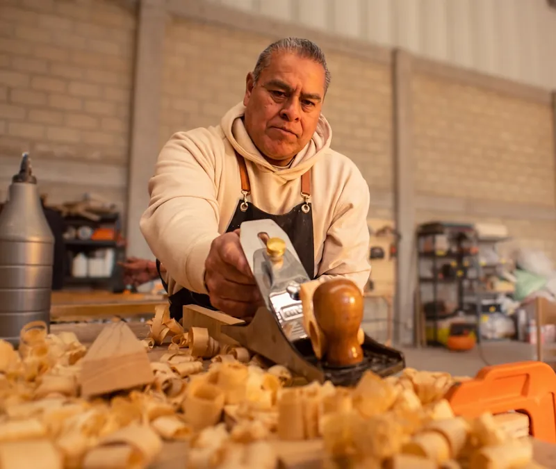 Carpintero cepillando madera a mano en el taller de Lerma